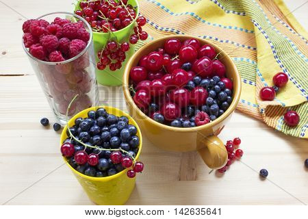 Assorted berry on a wooden table: cherries blueberries currants raspberries.