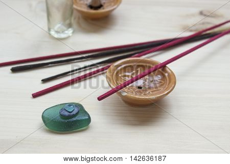 Blue spa stones and aroma sticks with a ceramic stand on a wooden background.