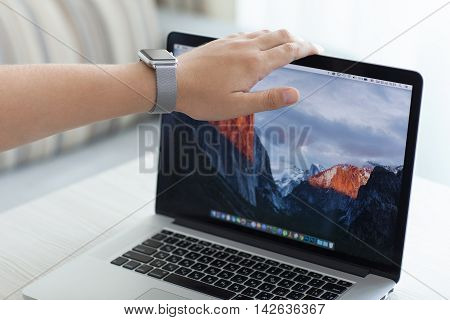 Alushta Russia - July 30 2016: Apple Watch on man hand open MacBook Pro with wallpaper macOS Sierra on the screen. Apple Watch and Macbook Pro was created and developed by the Apple inc.