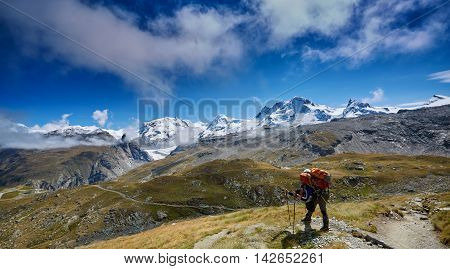 tired hiker with backpack on the trail in the Apls mountains. Trek near Matterhorn mount