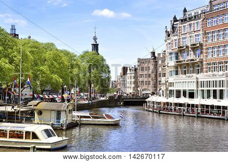 Cityscape of Amsterdam, the Netherlands, with tour boats and church tower.