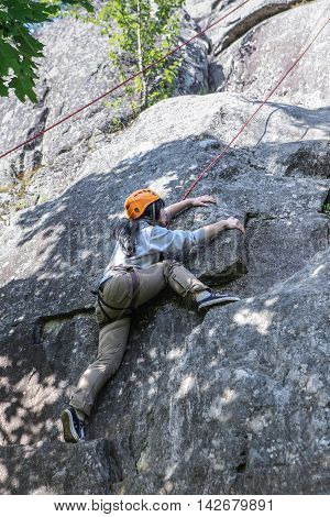 Karelia Russia - June 24 2016: pretty young woman practicing climbing on natural rocks spending so her active leisure