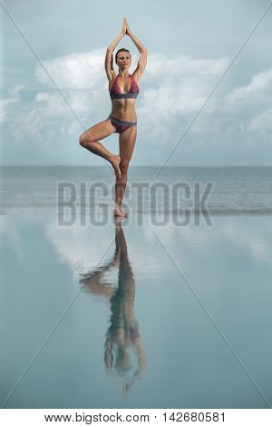 Yoga by woman on the beach near the ocean