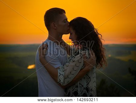romantic couple at sunset on outdoor, beautiful landscape with bright yellow sky, love tenderness concept, young adult people