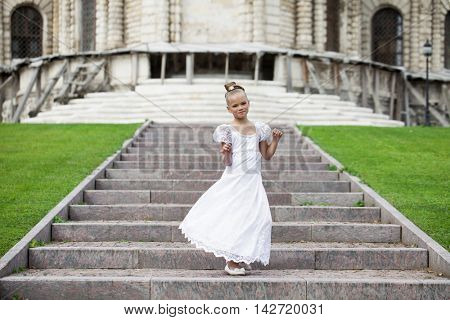 Portrait of a beautiful young little girl in white gown, summer outdoors