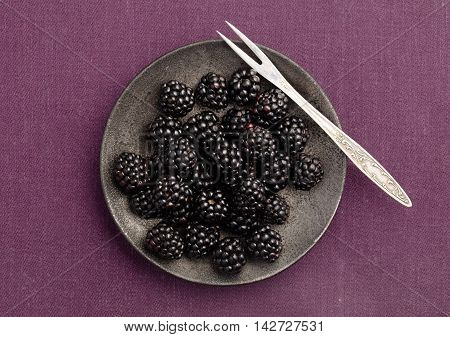 Blackberries plate on magenta tablecloth. Top view