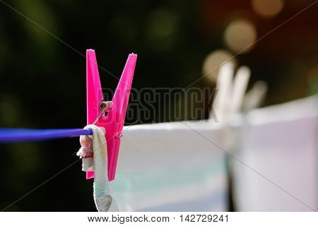 Clothespins holding laundry on the drying line drying clothes outside on fresh air wind and sun. Housework family life household natural living and lifestyle concept.