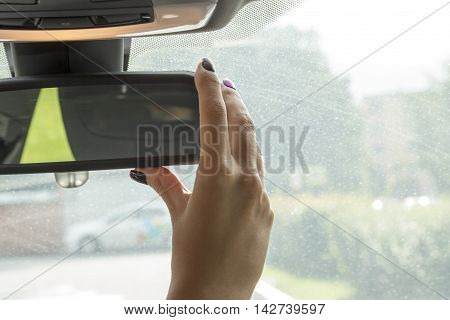 the girl in the cabin of the car  adjusts the rear view mirror