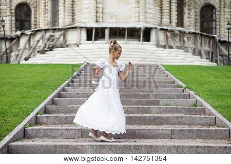 Portrait of a beautiful young little girl in white gown, summer outdoors