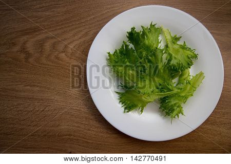 green lettuce leaves in a white mask on wood background