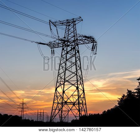 Electric pole connect to the high voltage electric wires on sunset sky background