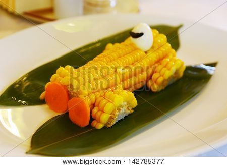 boiled corn car with carrot frontlights and quail egg driver close up photo on the plate