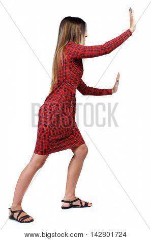 back view of woman pushes wall.  Isolated over white background. Rear view people collection. backside view of person. The girl in red plaid dress that pushes it ahead.
