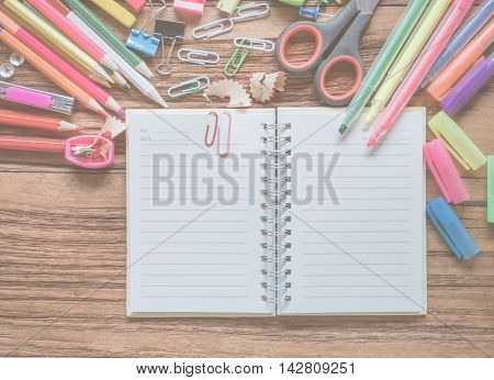 Top view notebook and office suplies on wood table made soft focus style