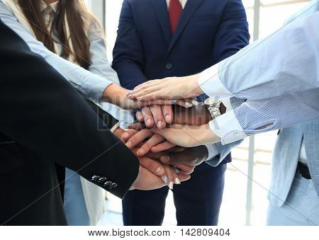 Multiethnic group of young people putting their hands on top of each other. Close up image of young business people making a stack of hands.