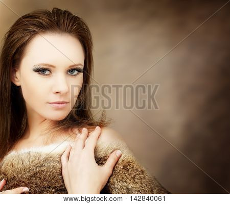 Beautiful woman in furs on brown background