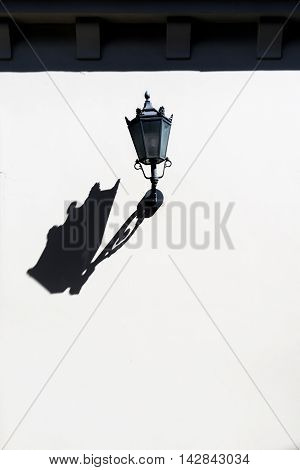 Street lamp with a long beautiful shadow on the wall of the facade clean house Riga