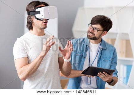 Check it out. Cheerful colleagues using virtual reality device while testing it and working together