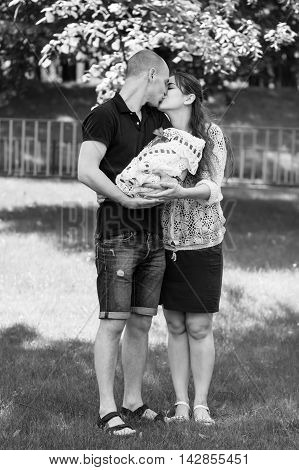 Happy Couple Holding Their Newborn Daughter In Her Arms. Outdoors.black And White Photography