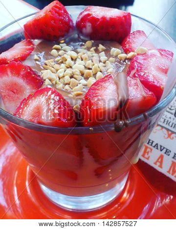Pretty chocolatepudding decorated with strawberries and almondsprinkles.
