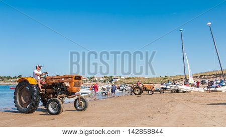 Men Getting Boats Out Of Water With Tractors On The Beach