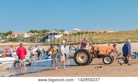 Men Getting Boats Out Of Water With Tractors On The Beach