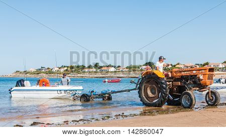 Men Getting Boats Out Of Water With Tractors On The Beach