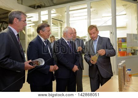 ST. PETERSBURG, RUSSIA - AUGUST 11, 2016: Director of the Heineken brewery Oleg Bokov shows the grains to vice-governor of St. Petersburg Igor Divinsky (center) during his working visit to enterprise