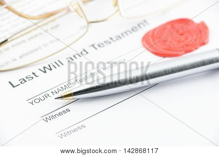 Blue ballpoint pen on last will and testament with eye glasses and a sealing wax stamped with alphabet letter B. Preparation for filling and signing a document.