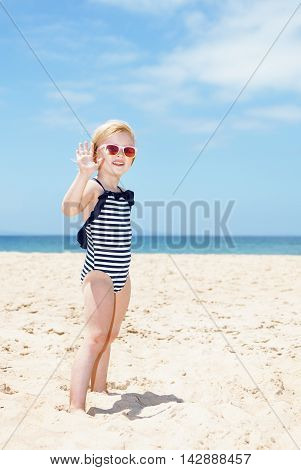 Happy Girl In Striped Swimsuit On A White Beach Handwaving