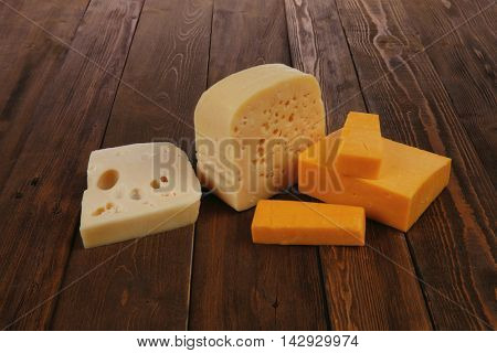 various types of fresh raw aged delicatessen cheese on wooden table cheddar edam swiss