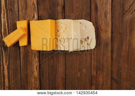 various types of fresh raw aged delicatessen cheese on wooden table cheddar edam swiss