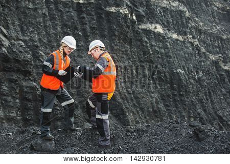 Two speacialists examining coal at an open pit