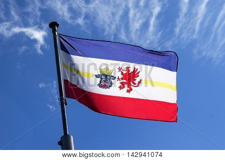 flag of Mecklenburg-Vorpommern blowing in the wind against the blue sky a symbol of the federated state on the Baltic Sea in northeastern Germany with the bull's head for Mecklenburg and the grasping of Vorpommern