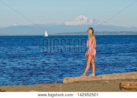 Woman on beach looking at sail boat. Centennial Beach in Boundary Bay Regional Park Tsawwassen British Columbia Canada