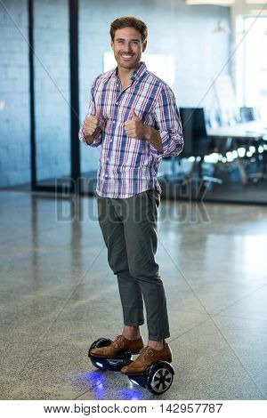 Portrait of graphic designer standing on hoverboard in office