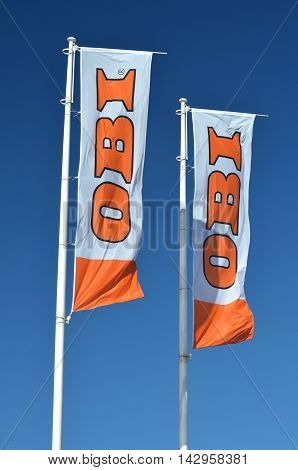 CIRCA AUGUST 2016 - GDANSK: sign of OBI on waving flags against blue sky. OBI is the largest do it yourself retailer in Europe. It was founded in 1970 in Hamburg, Germany.