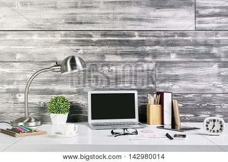Creative hipster workplace with blank laptop computer tablet coffee cup table lamp clock and other items. Mock up