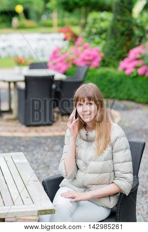 Happy beautiful young studient girl with white smart phone outdoors on holiday texting and smiling
