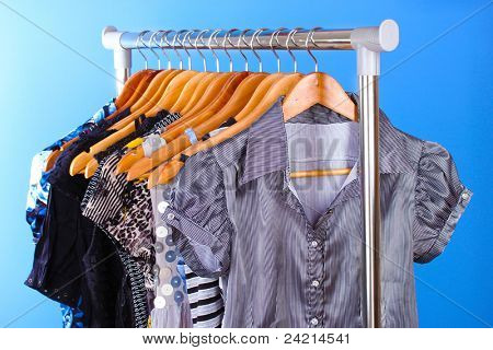 เสื้อผ้าต่าง ๆ บนไม้ hangers บนพื้นหลังสีน้ำเงิน
