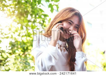 Happy Asian Girl Talking With Mobile Phone Front Of High Building.