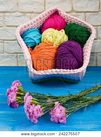 Knitted Handmade Basket And Blue Carnations On The Shabby Boards.