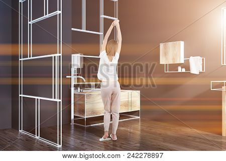 Futuristic Bathroom Corner With Black Walls, A Wooden Bathtub, A Mirror And A Glass Wall. A Woman St