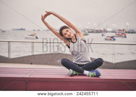 Sports Concept. Beautiful Girl Is Exercising On The Beach With Warm Up. Beautiful Girl Is Happy To E