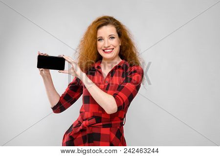 Charming Young Girl In A Checkered Cloth On A Gray Background