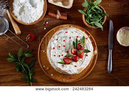 Strawberry Tart Covered With Whipped Sour Cream Surrounded By Organic Ingredients Over Wooden Backgr