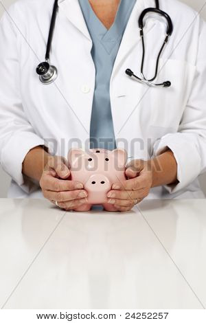 돼지 저금통에 돌보는 손으로 여성 의사.