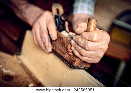 detail, old carpenter hands at work with handplaner