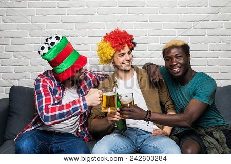 Three Happy Men Sitting On Couch And Watching Sport On Tv.