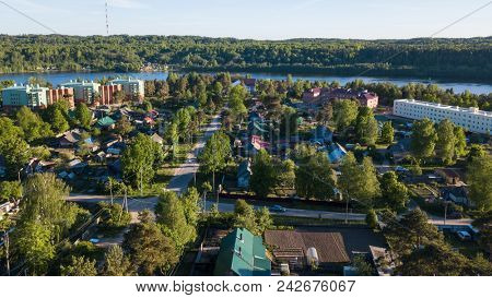 Russian village with wooden houses. Svir river and summer green forests of Leningrad region, Russia. Flying over roofs. 